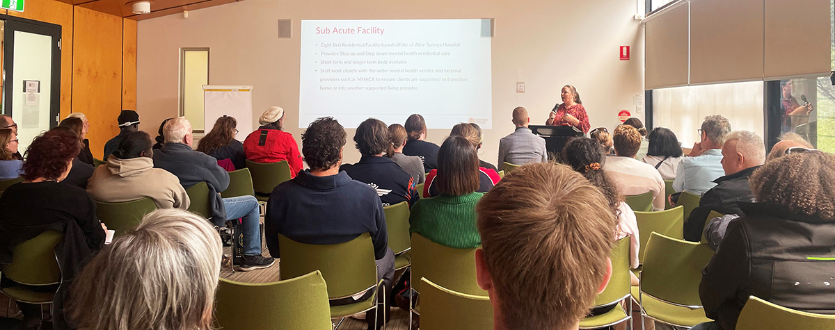 A group of people sitting in a building watching a presentation.